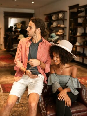A man and woman enjoying shopping in a stylish boutique, surrounded by hats.