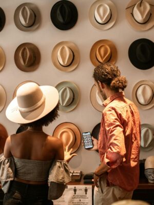 A stylish couple exploring a hat boutique, showcasing diverse headwear.