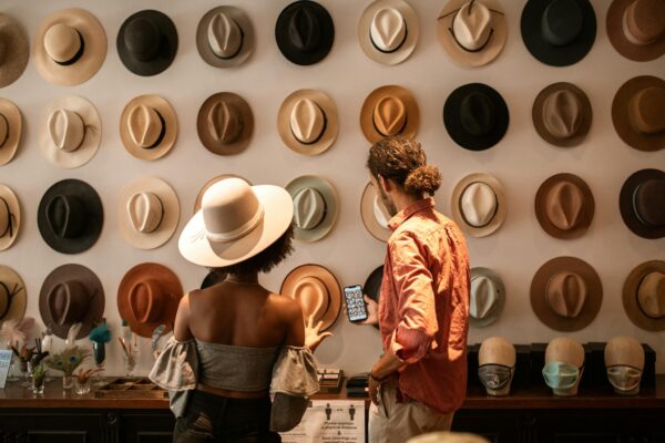A stylish couple exploring a hat boutique, showcasing diverse headwear.