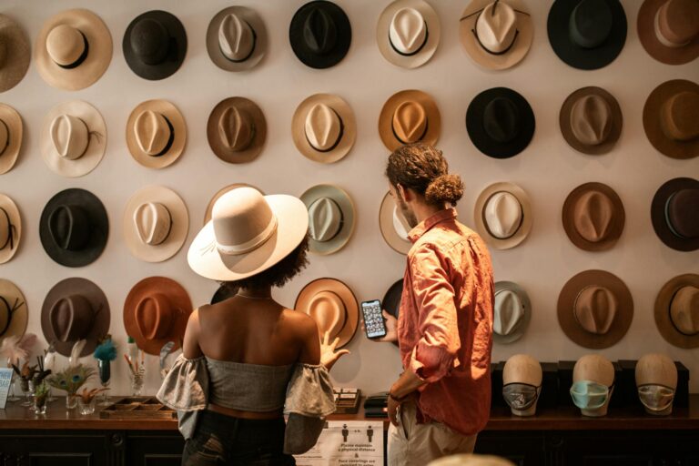 A stylish couple exploring a hat boutique, showcasing diverse headwear.