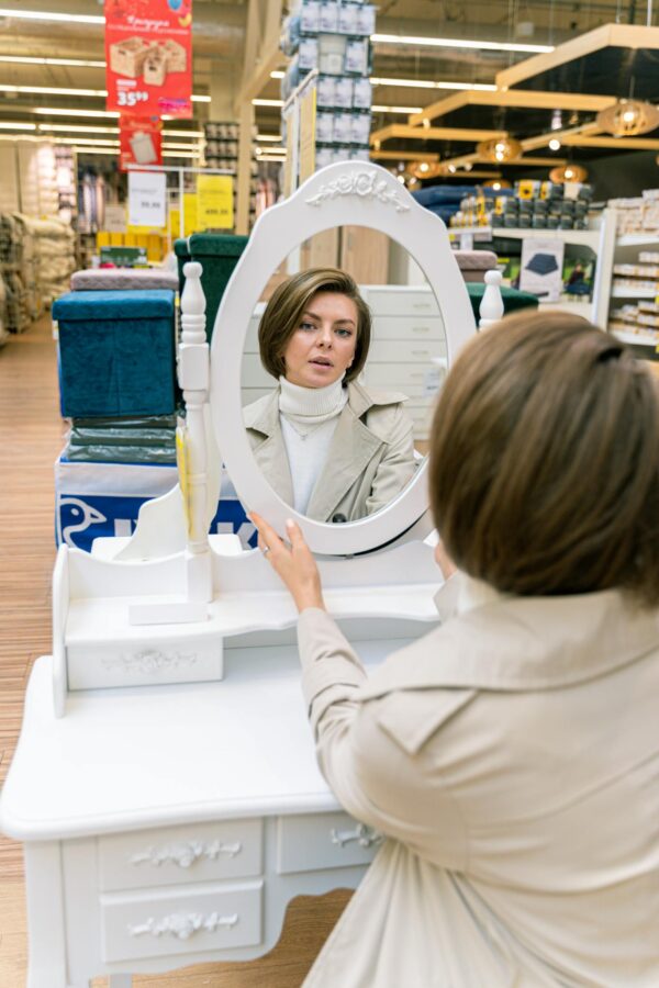 A stylish woman examines her reflection in a store's mirror.