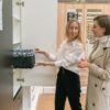 Two women shopping for baskets in a furniture store, discussing choices.